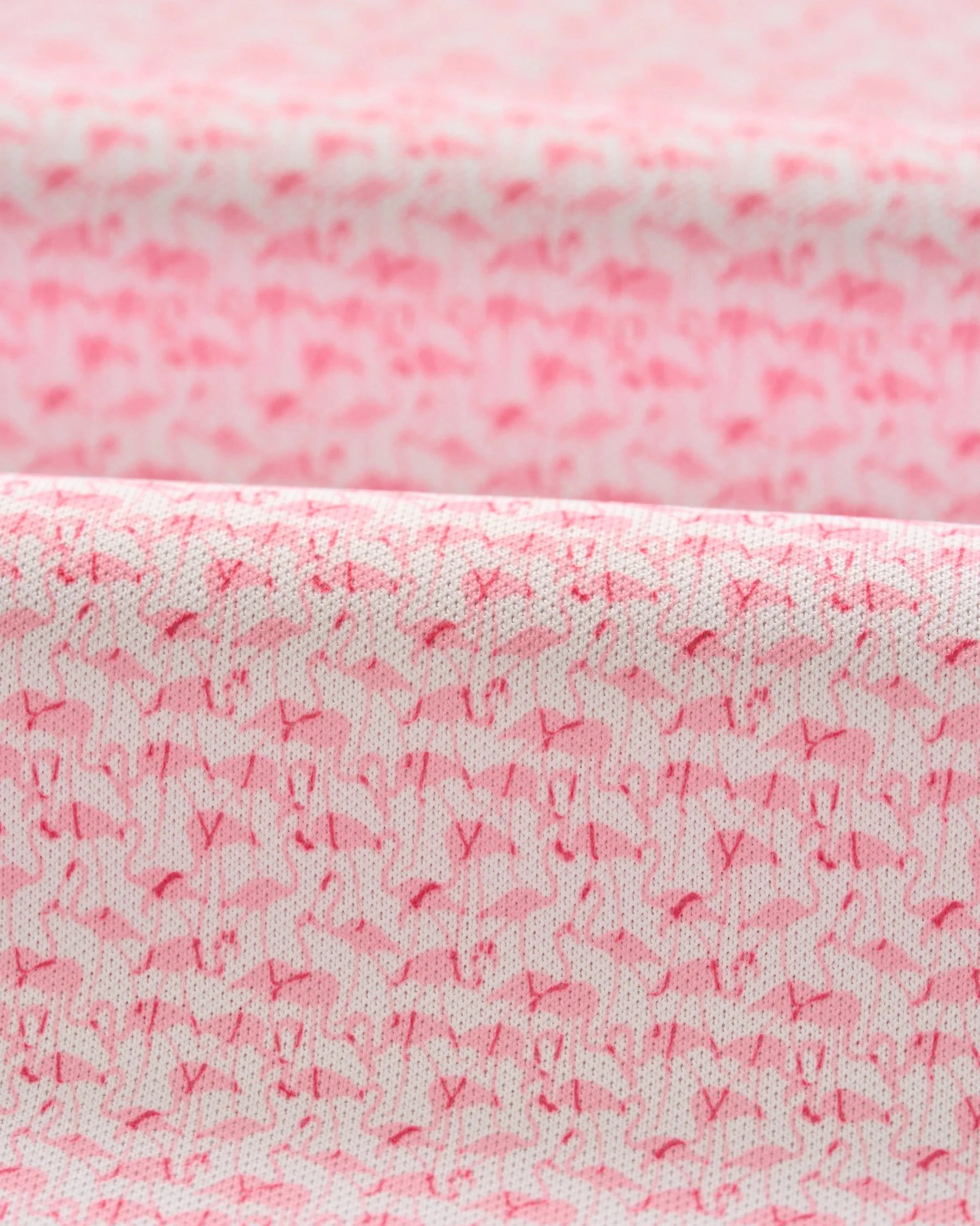Close-up of the Johnnie-O Flock Yeah Performance Mesh Polo's pink fabric, featuring small abstract animal shapes in a darker pink shade.