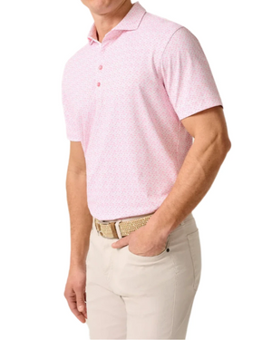 A man wearing the Johnnie-O Flock Yeah Performance Mesh Polo in light pink, paired with beige pants and a woven beige belt, stands with one hand in his pocket.
