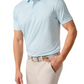 A man wearing the Johnnie-O Huronn Featherweight Performance Polo with UPF 50 sun protection, beige pants, and a patterned belt stands with one hand in his pocket against a white background.