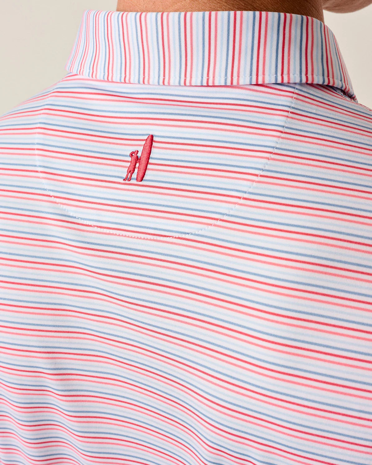 Close-up of the back of the Johnnie-O Kamdon Performance Jersey Polo with blue, white, and red stripes and a red embroidered surfboard figure below the collar. Made from moisture-wicking fabric for all-day comfort.