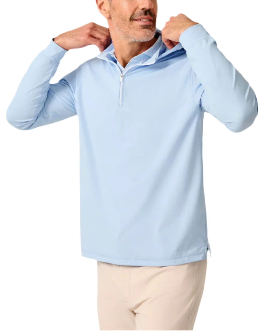 A man in a Johnnie-O Robby Performance 1/4-Zip Hybrid Hoodie, light blue, pairs it with beige pants and adjusts the collar while facing slightly right against a plain background.