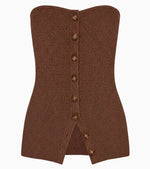 Ulla Johnson’s Yanni Strapless Knit Top is a brown ribbed knit tube top featuring a corset-inspired front with eight button closures and a small slit at the hem—the perfect statement piece.