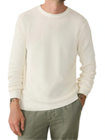 A person wearing the Faherty Sunwashed Crewneck Sweater in white and olive green pants, with hands in their pockets, shown from shoulders to thighs.