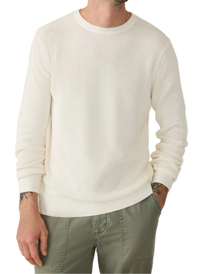 A person wearing the Faherty Sunwashed Crewneck Sweater in white and olive green pants, with hands in their pockets, shown from shoulders to thighs.