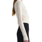 A woman wearing the Altuzarra Arlette Sweater—a cream ribbed knit with two-tone metal buttons—paired with a high-waisted black skirt stands sideways against a white backdrop.