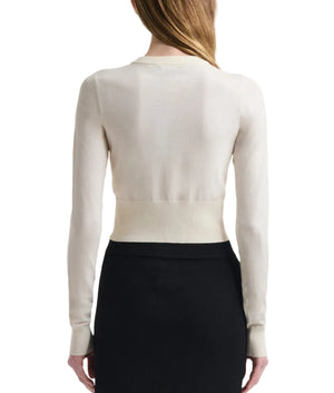A woman is seen from the back wearing the Arlette Sweater by Altuzarra, a fitted off-white ribbed knit, paired with a high-waisted black skirt.