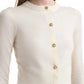 A close-up of a person wearing the Arlette Sweater by Altuzarra, a cream ribbed knit with two-tone metal buttons, shown from shoulders to waist against a white background.