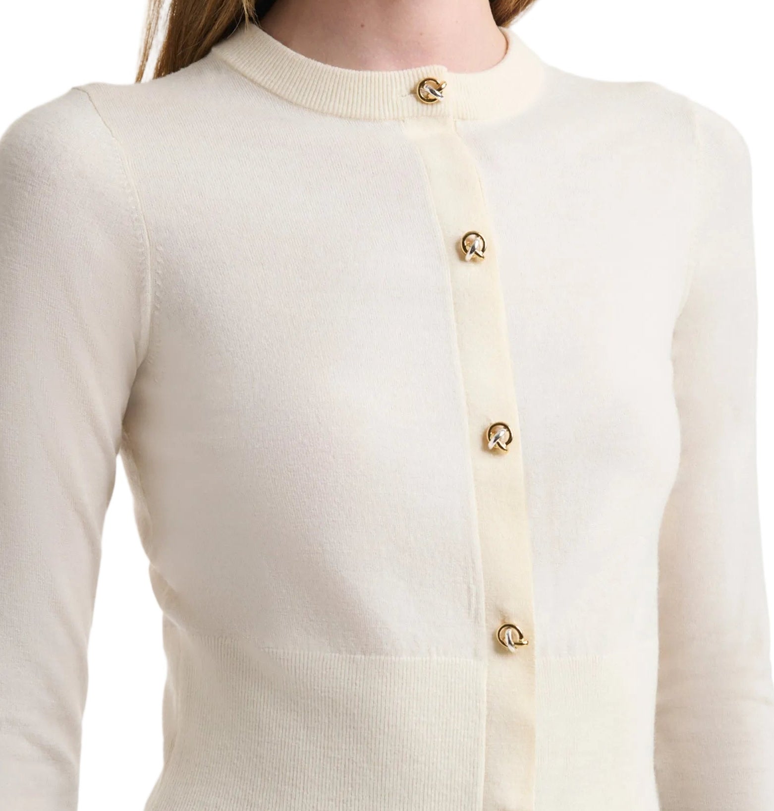 A close-up of a person wearing the Arlette Sweater by Altuzarra, a cream ribbed knit with two-tone metal buttons, shown from shoulders to waist against a white background.
