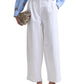 A person wearing white Dash Pant from Altuzarra, a light blue striped shirt, tan flat shoes, and holding a small beige clutch.