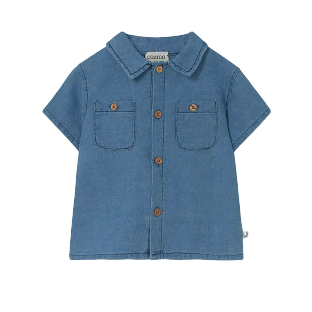 The Cozmo Baby Boys' Forest Chambray Shirt features blue denim, short sleeves, two chest pockets, brown buttons, and a collar, shown on a white background.