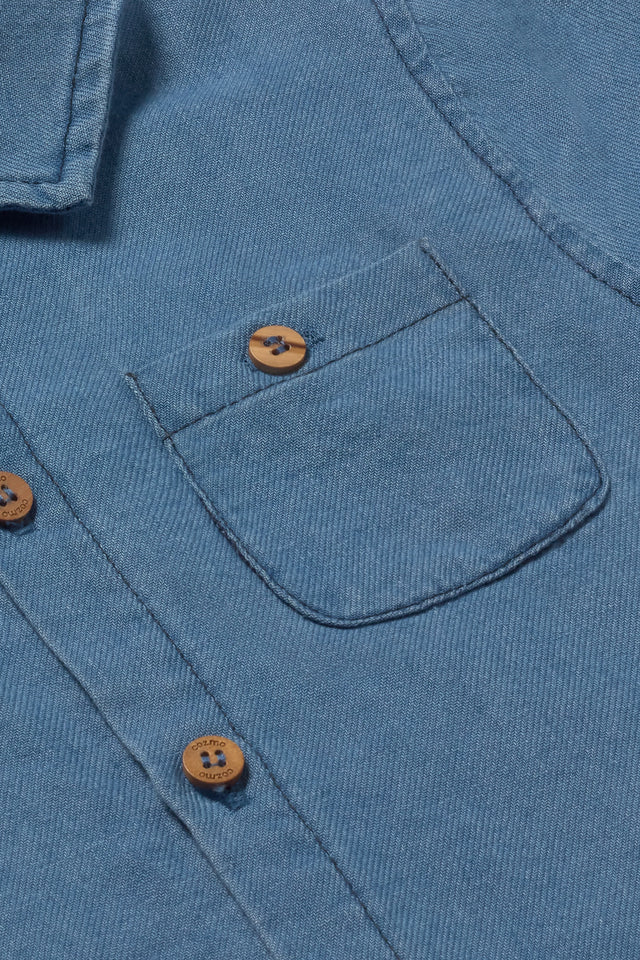Close-up of Cozmo’s Baby Boys' Forest Chambray Shirt in blue, highlighting the chest pocket and brown buttons—an ideal casual shirt for boys.