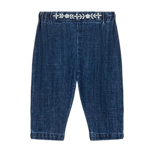 Louise Misha Baby Girls' Flofia Pants in dark blue denim with an elastic waistband and delicate white embroidery along the top, shown flat on a white background.
