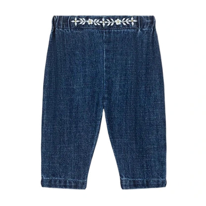 Louise Misha Baby Girls' Flofia Pants in dark blue denim with an elastic waistband and delicate white embroidery along the top, shown flat on a white background.