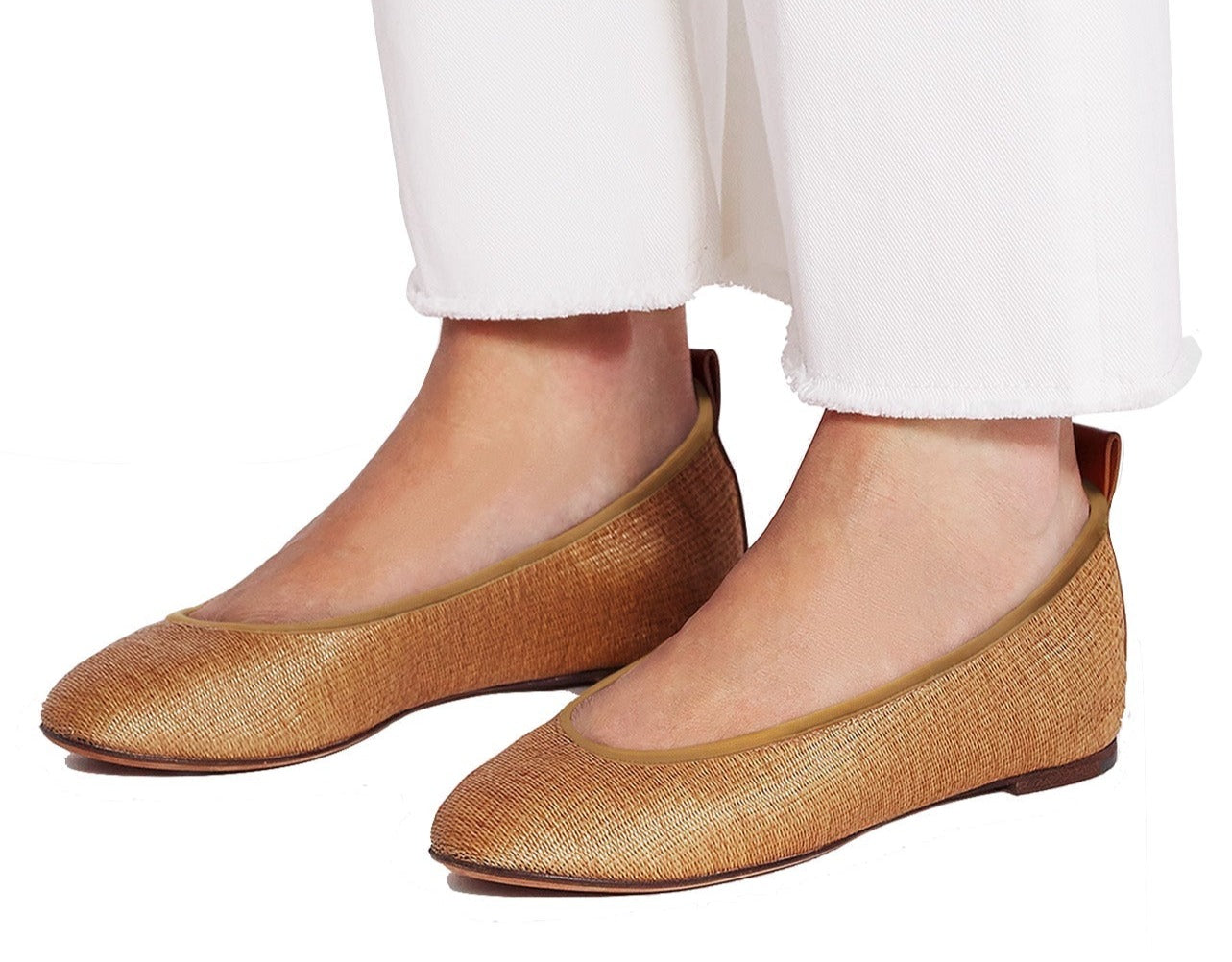 A person wearing white pants is shown from the knee down, modeling a pair of elegant, brown textured flats. This casual outfit is complemented perfectly by the Lanvin Raffia Ballerina shoes from Lanvin.