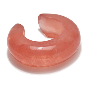 The Arc Marbled Cuff by Lizzie Fortunato features a smooth, polished pink marbled resin and an open-ended domed design—an eye-catching statement piece shown on a white background.