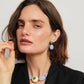 Woman with short brown hair wears a black top, blue and cream beaded necklace, and Lizzie Fortunato Andalusia Earrings featuring blue chalcedony and green chrysoprase as she looks at the camera.