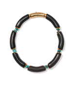 The Cathedral Collar by Lizzie Fortunato is a black horn beads necklace with curved segments, small turquoise stones, gold accents, and a gold clasp.
