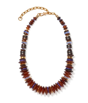 The Amaranth Necklace by Lizzie Fortunato features amber heishi and gold-plated beads, accented with graduated brown, blue, and metallic discs, finished with a gold-toned adjustable chain clasp.