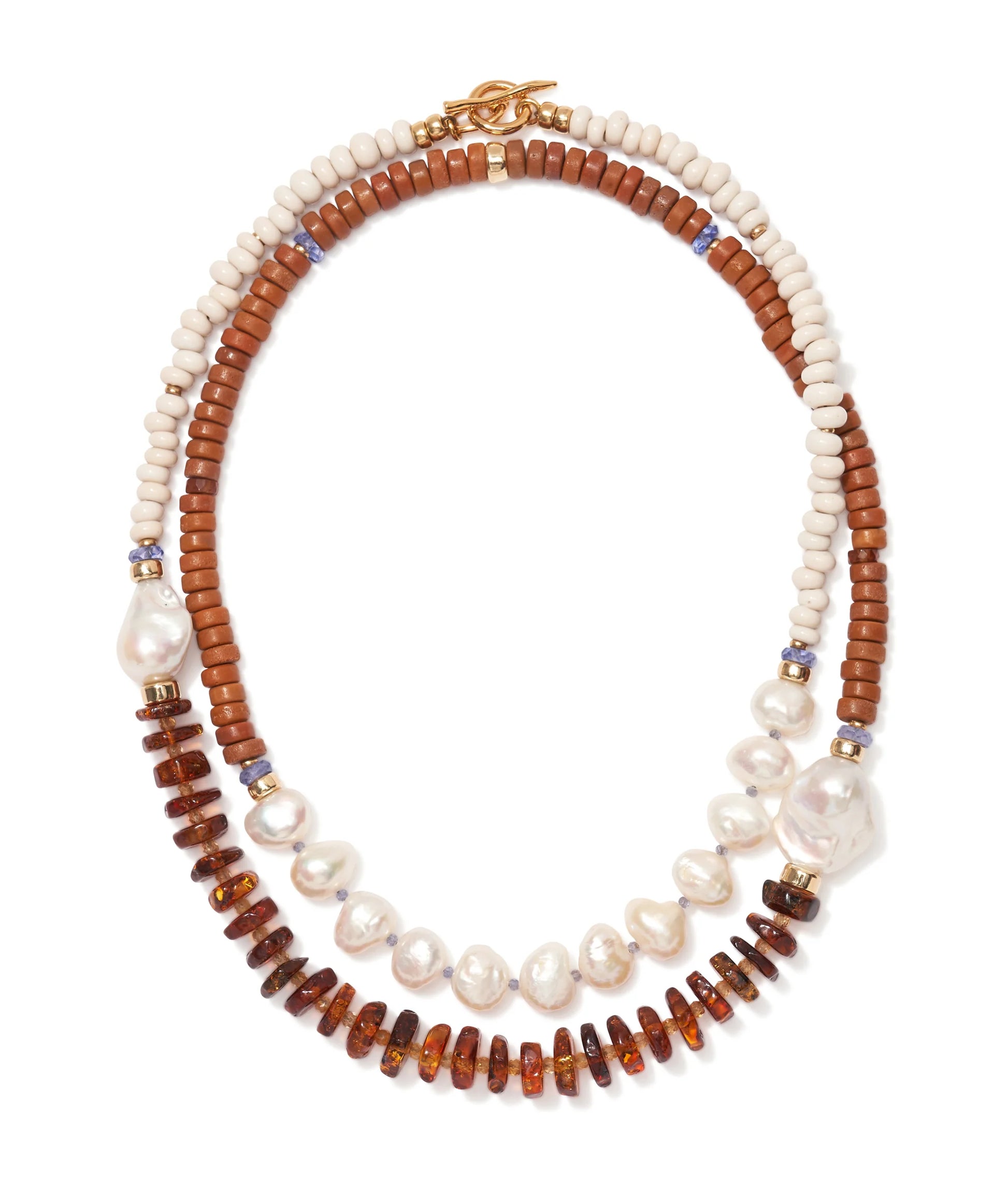 The Cabana Necklace by Lizzie Fortunato showcases two strands—one with white and brown beads, the other with pearls, amber discs, and blue accents—finished with a gold clasp. A statement piece to elevate any outfit.