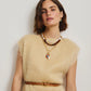A woman with short brown hair wears a beige textured top, small earrings, a brown belt with a heart-shaped buckle, and layers the Lizzie Fortunato Cabana Necklace, standing against a plain light background.