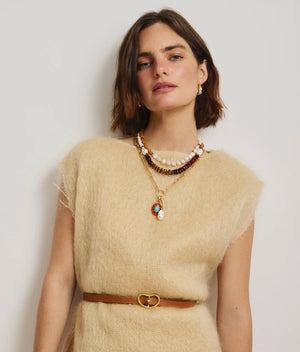 A woman with short brown hair wears a beige textured top, small earrings, a brown belt with a heart-shaped buckle, and layers the Lizzie Fortunato Cabana Necklace, standing against a plain light background.