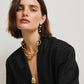 Woman with short brown hair wears a black outfit, the Lizzie Fortunato Campo Charm Necklace, and black and turquoise earrings against a plain light background.