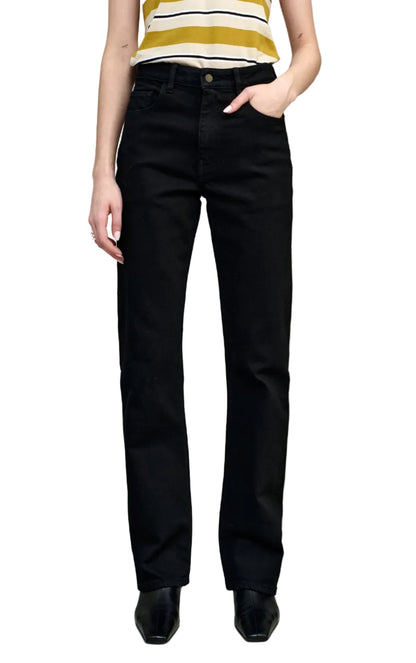 A person is wearing the Kallmeyer Farah Classic Bootcut jeans—black stretch cotton denim with a mid-high rise and straight-leg fit—styled with a sleeveless striped top, standing with one hand in their pocket against a white background.