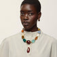 A person wearing a cream button-up shirt, Lizzie Fortunato Zellige Hoops, and a colorful chunky beaded necklace stands against a plain light background.