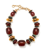 The “Carmine Collar” by Lizzie Fortunato showcases chunky burgundy acrylic beads, gold-plated discs, smaller turquoise and dark accents, all finished with a sleek gold clasp.