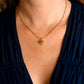A person wearing the Anabel Aram Heart Locket Necklace, an 18k gold heart-shaped pendant with a scalloped edge, styled as keepsake jewelry and paired with a dark V-neck top.