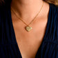A person wears the Anabel Aram Heart Locket Necklace, a gold dipped brass piece, as a cherished keepsake with a dark V-neck top.