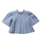 The Girls’ Jaipur Top by Pink Chicken features a light blue fabric adorned with a small red and green floral pattern, and is designed with a high collar, pleated front, wide bell sleeves, and finished with navy glitter buttons.