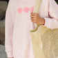 A person wearing the Feather 4 Arrow Baby Girls’ and Girls’ Weekend Sweatshirt in light pink, featuring three pink shell designs in a trendy puff print, holds a large woven tote bag.