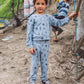 A young boy wears the Feather 4 Arrow Baby Boys’ and Boys’ Icon Hacci Set—crafted from ultra-soft hacci fabric—as he stands outdoors on the dirt, while another child enjoys climbing ropes in the background. This set is perfect kids loungewear for playtime adventures.