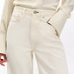 A person wearing Rag & Bone’s Featherweight Logan cream-colored button-up shirt and matching wide leg jeans, with one hand in their pocket.