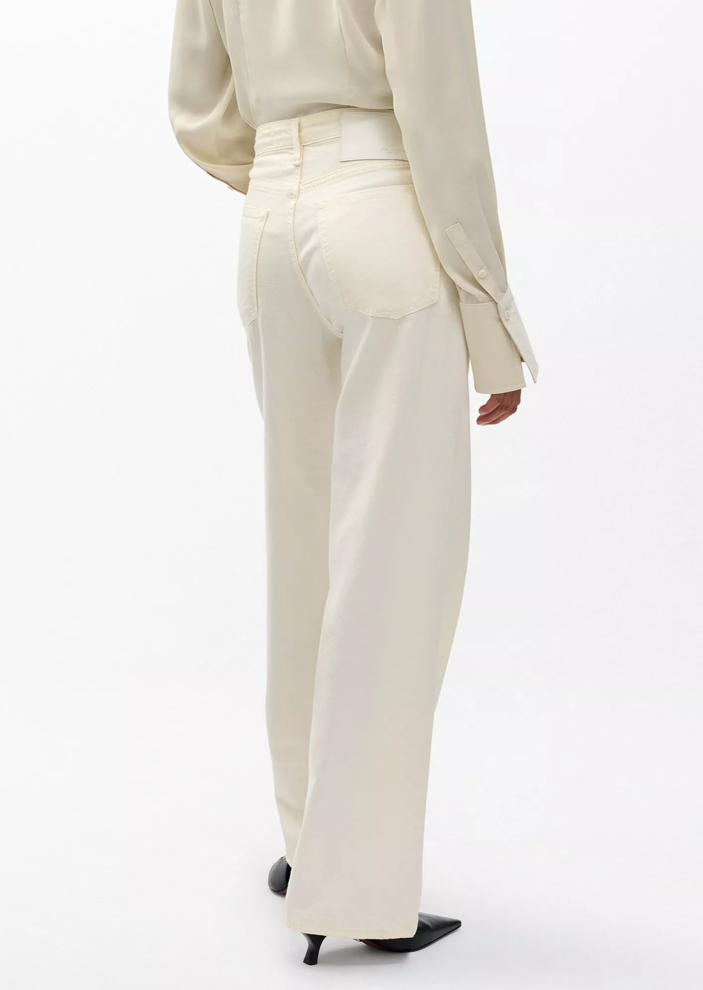 Person wearing an off-white long-sleeve shirt and Rag & Bone Featherweight Logan high-waisted wide leg jeans, photographed from the back against a plain background.