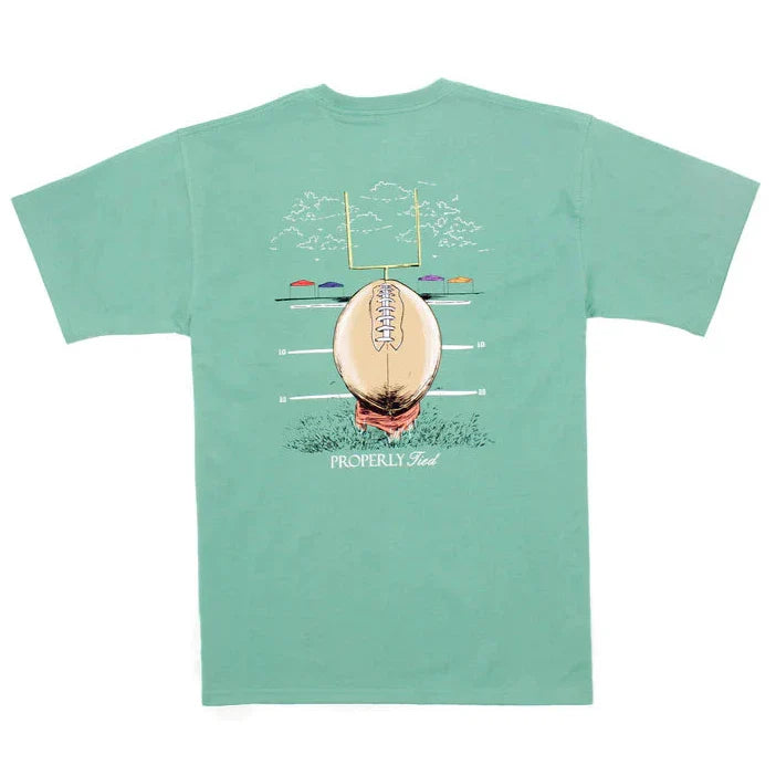 The Properly Tied Boys Field Goal SS Tee is a stylish green t-shirt featuring an illustration of a football and goalpost, complemented by palm trees and beach umbrellas. Combining comfort with classic design, it includes the text "Properly Tied," making it ideal for those who appreciate timeless styles.