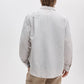 A person with light brown hair is wearing the Rag & Bone Finch Linen Stripe Shirt—a relaxed fit, button-up striped shirt—paired with beige pants, standing facing away from the camera against a plain white background.