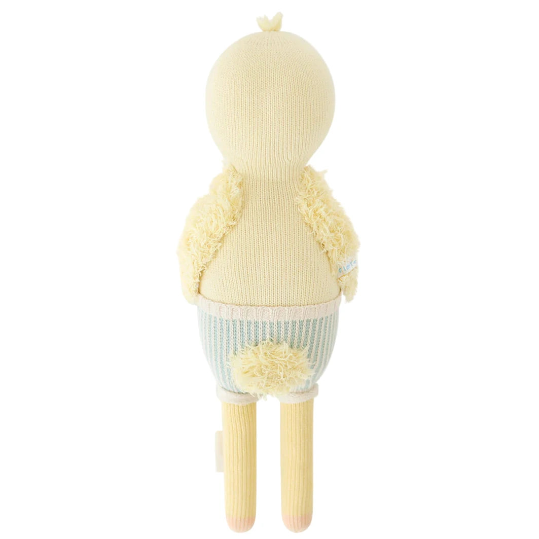 Finley the Duckling by Cuddle + Kind is a 20" knitted plush toy with a fluffy yellow vest, small tail, and long legs—perfect as a charming birthday gift.