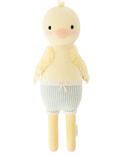 Finley the Duckling - Little 13" by Cuddle + Kind is a knitted yellow plush toy, designed with a round head, pink cheeks, short wings, and blue-and-white striped shorts topped with a decorative bow—making it an adorable birthday gift for any child.