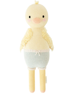 Finley the Duckling by Cuddle + Kind is a 20" knitted yellow plush with fluffy wings, pink cheeks, and blue striped shorts—an adorable choice for a birthday gift.
