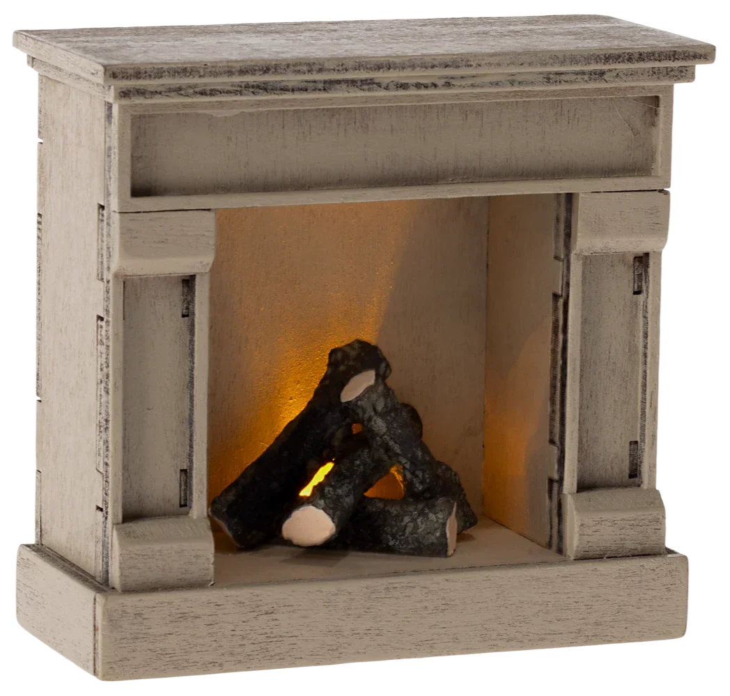 The Maileg Fireplace, Mouse - Off White by Maileg features a compact decorative wooden design with faux logs that emit a warm, orange glow, beautifully complemented by its vintage finish.