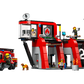 The LEGO® Fire Station with Fire Truck set includes minifigures, a dog, drone, and accessories outside a red and gray building marked with a "2" and flame—ideal for firefighting adventures from LEGO®.