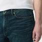 A person wearing Rag & Bone Fit 2 Authentic Stretch Denim jeans in a dark indigo wash and a white shirt, with their right hand resting by their side.