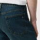 A person wears Rag & Bone Fit 2 Authentic Stretch Denim jeans in dark indigo, paired with a white shirt, shown from the waist down with emphasis on the back pocket.