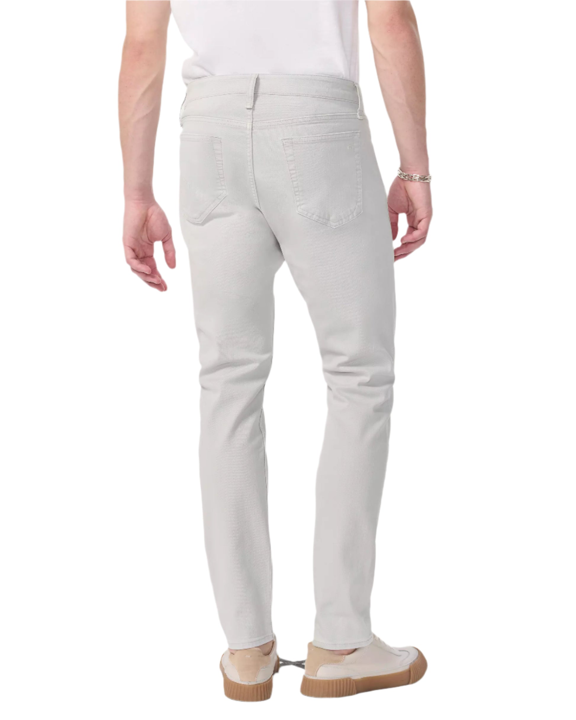 A person is seen from the back wearing Rag & Bone Fit 3 Aero Stretch Athletic Jeans in light gray, a white T-shirt, and beige shoes.