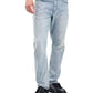 Someone wearing Rag & Bone Fit 3 Authentic Stretch light indigo jeans, a white shirt, and black shoes stands with one hand in their pocket.