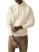 Someone is wearing a Faherty High Standard Fleece Hoodie in beige, made from organic cotton, paired with brown pants against a white background.