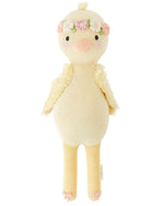 Cuddle + Kind’s Flora the Duckling, Mauve - Regular 20" is a knitted plush toy with pink cheeks and a floral headband, standing upright as if dancing among wildflowers against a white background.