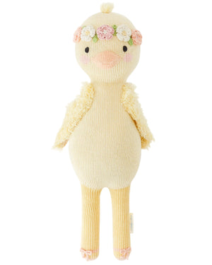 Flora the Duckling Mauve - Little 13" by Cuddle + Kind is a knitted plush yellow duck with a floral headband and textured wings, posed upright against a white background.